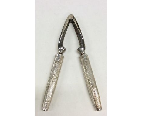 A pair of silver engine turned nut crackers. Approx. 188 grams. Est. £20 - £30.