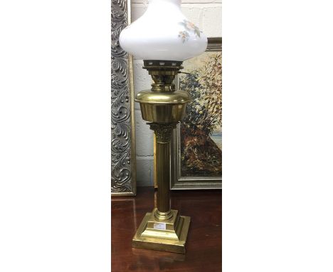 A brass Corinthian column lamp with glass shade.