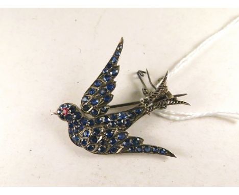 An early 20th century white metal brooch in the form of a swallow set with sapphires and a ruby eye