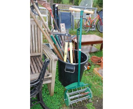  A black plastic dustbin containing garden tools, draining rods, bow saw, and lawn aerator.