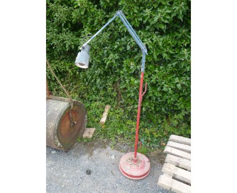 A floor-standing angle-poise style adjustable lamp mounted on a vehicle brake hub.