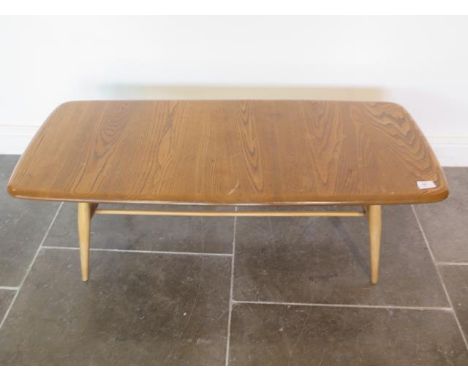 An Ercol light elm coffee table with rack, 37cm x 105cm x 43cm, some marks consistent with use but otherwise good 