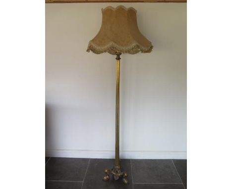 A brass colomn standard lamp on triform scroll and claw feet, 193cm tall, will need rewiring but in generally good condition 