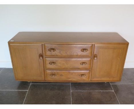 A light Elm Ercol sideboard with two doors and three central drawers on caster, 69cm tall x 156cm x 47cm, some small wear but