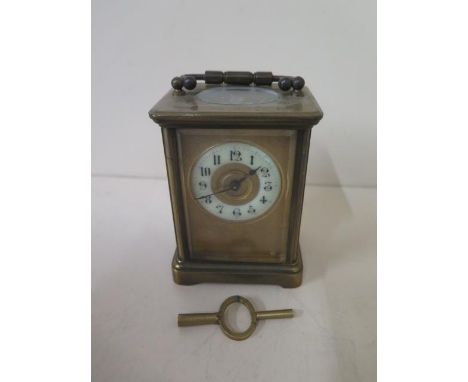 A brass carriage clock with key, running, 11cm tall with handle down, one glass panel chipped otherwise generally good 