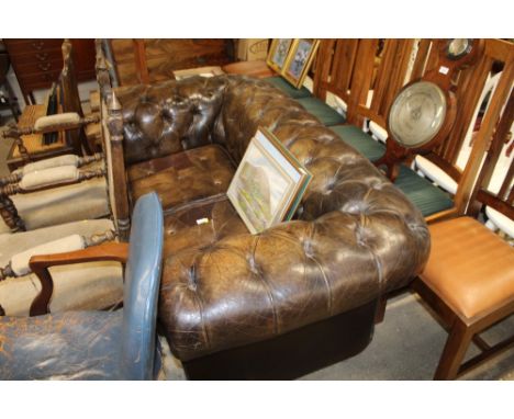 A leather chesterfield two seater sofa with various leather patch repairs