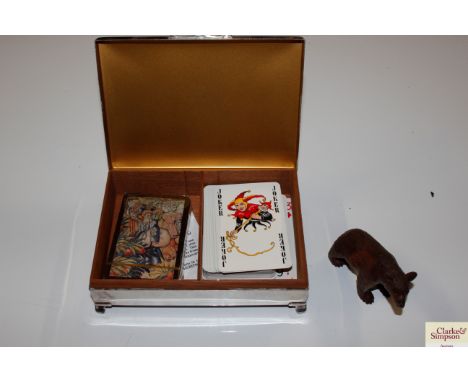 A silver plated engine turned decorated cigarette box, contents of playing cards and a Black Forest type carved bear