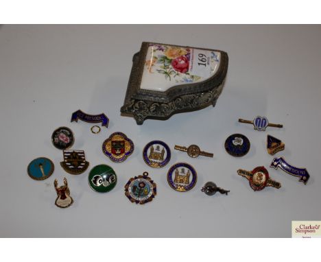 A ring box in the form of a grand piano with floral porcelain top and contents of various enamel badges