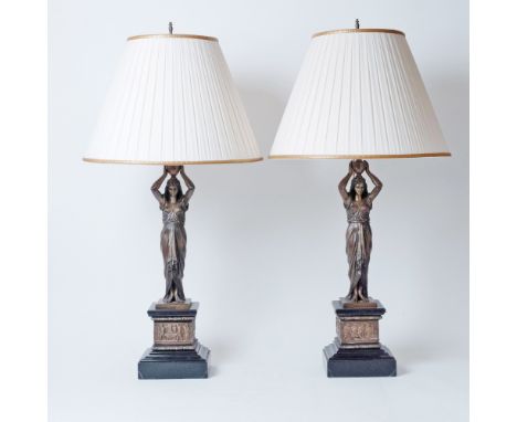 20th century. Each item in the shape of a classical maiden, raised on a square stepped black marble base. Mounted with a gilt
