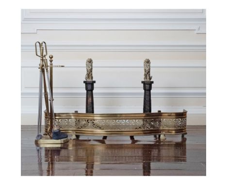 Comprising a pair of lion-form andirons, height 26 1/4 inches; brass serpentine fender; and a group of fire tools on stand.No