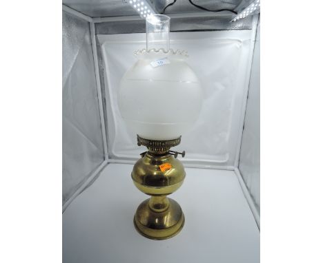 A brass oil burning lamp with etched shade