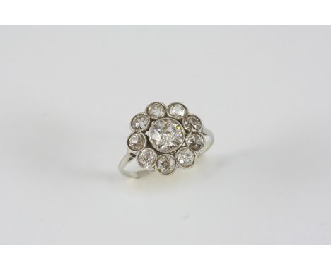 A EARLY 20TH CENTURY DIAMOND CLUSTER RING of flowerhead form, centred with an old brilliant-cut diamond within a surround of 