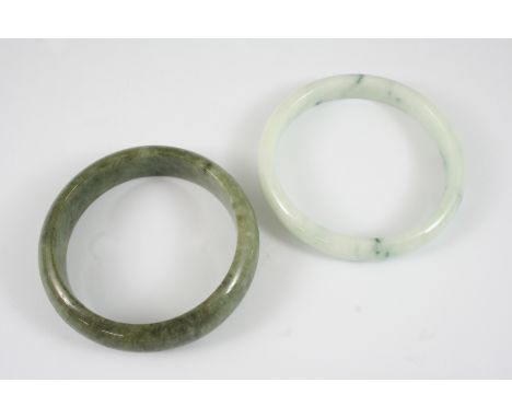 A MOTTLED GREEN JADE BANGLE together with another jade bangle.