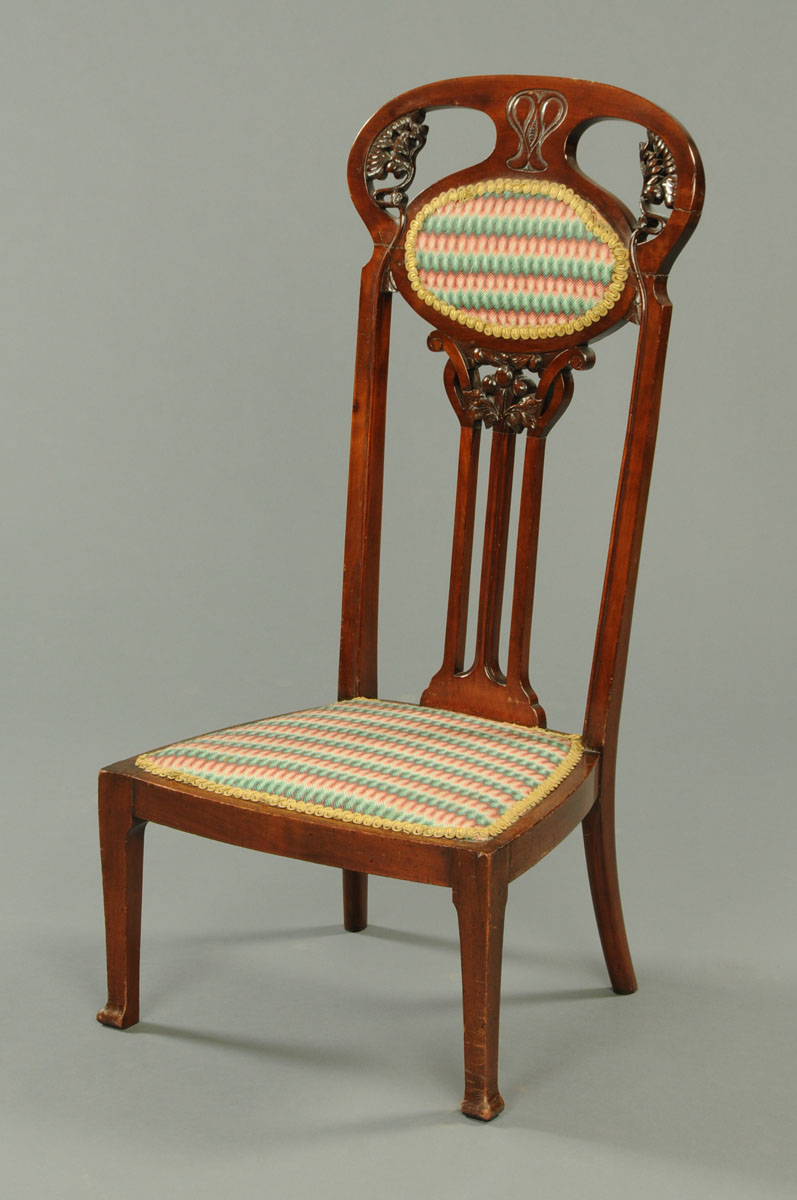 An Art Nouveau mahogany low chair, the back carved with stylised