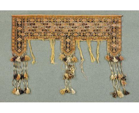 * An Afghan tent door surround, beige and brown, with tassels and metal pole.  Width 175 cm. 