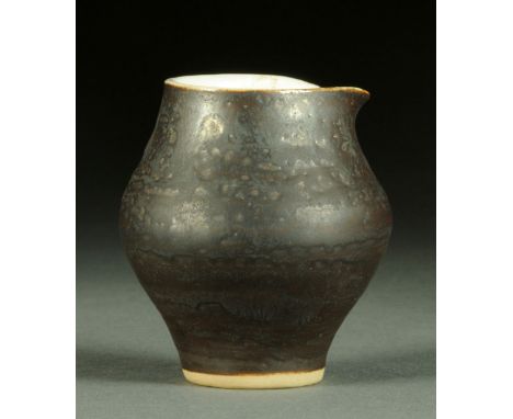 * Lucie Rie (1902-1995), a small jug, of baluster form with pinched lip, ferruginous glaze, impressed "LR" within foot.  Heig