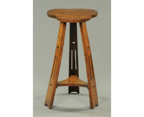 An Arts & Crafts oak occasional table, the top of shaped outline, with splayed supports and low shelf.  Width 37 cm.  CONDITI