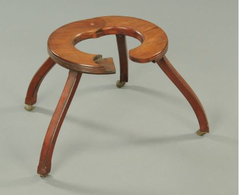 A Regency mahogany child's walking aid, circular and hinged and with four downswept legs terminating in roller castors.  Diam