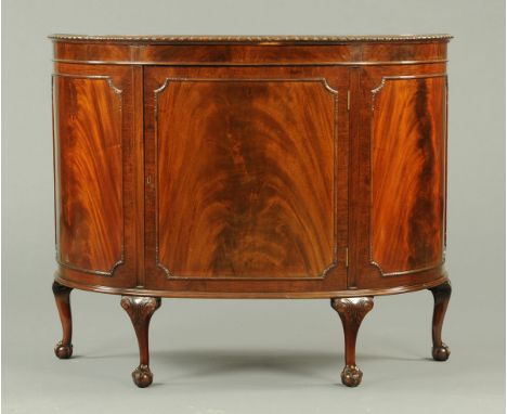 A mahogany demi-lune commode side cabinet, flanked on either side by a bowed panel and all raised on short cabriole legs term