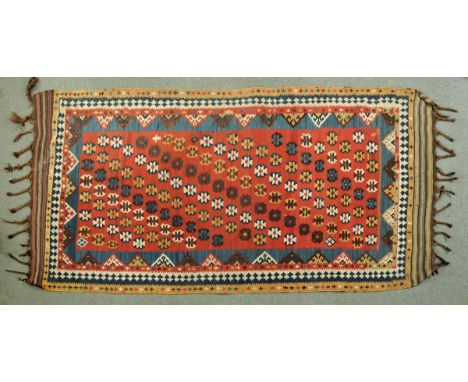 * A large Kelim rug, the centre rectangular panel with red ground and repeating motifs and with multiple line border and plai