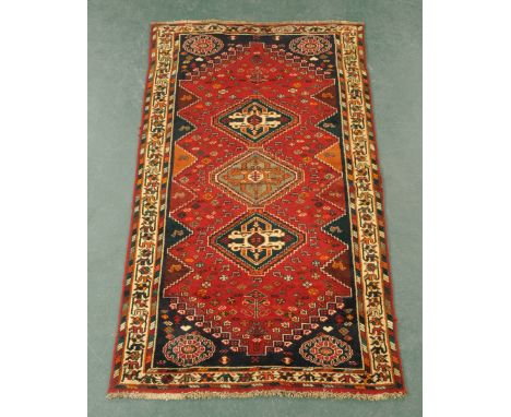 An Iranian woollen fringed rug, principal colours red, blue, black and beige.  211 cm x 120 cm (see illustration).