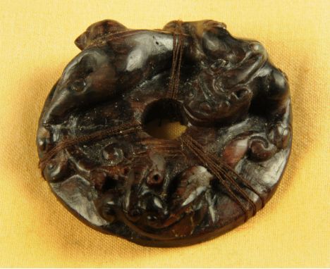 * A Chinese brown jade circular disc, pierced and decorated in relief with two stylised feline like dragons, Ming style.  Dia