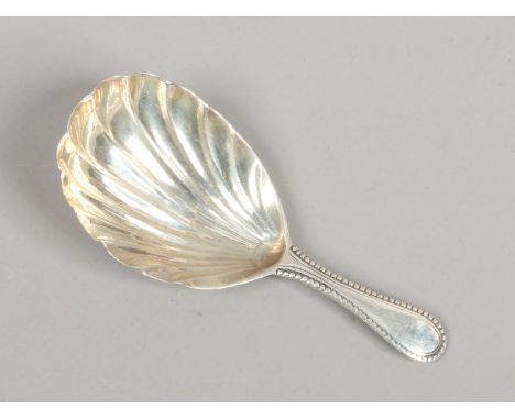 A silver caddy spoon with shell embossed bowl and beaded thread borders. Lion passant mark only.