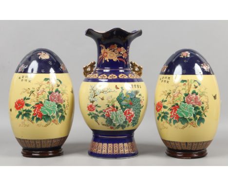 Two large Chinese decorative ceramic eggs raised on wood plinths along with a similar vase.