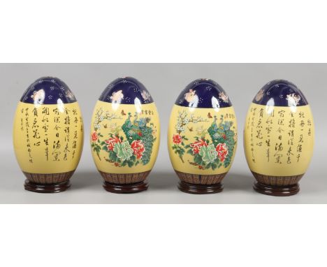Four Chinese decorative ceramic eggs raised on wood plinths.