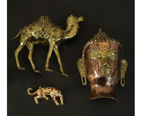 A collection of metal work items, a copper and brass Buddha head, a glass cabochon inlaid brass camel and an enamel and diama