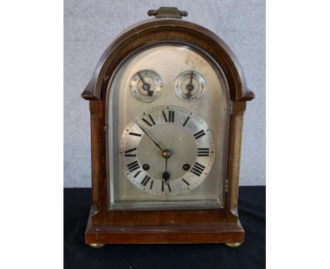 An early 20th century mahogany cased dome topped mantle clock, the silvered dial with two subsidiary dials raised on squat bu