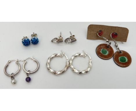 6 pairs of silver and costume jewellery earrings. To include twist style hoops, blue crystal ball studs, ladybird studs and e