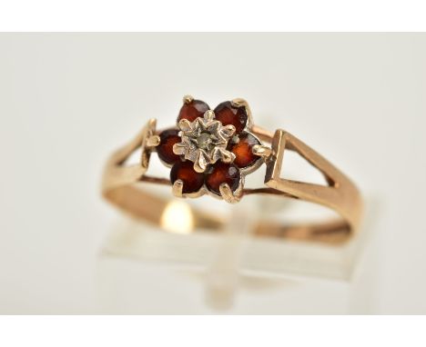 A 9CT GOLD GARNET AND DIAMOND CLUSTER RING, designed with a central single cut diamond, circular cut garnet surround, openwor