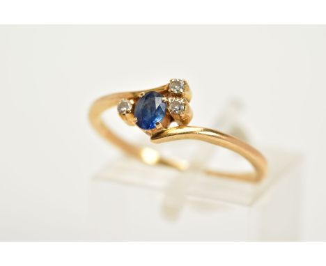 A SAPPHIRE AND DIAMOND YELLOW METAL RING, of cross over design set with an oval cut sapphire flanked with round brilliant cut