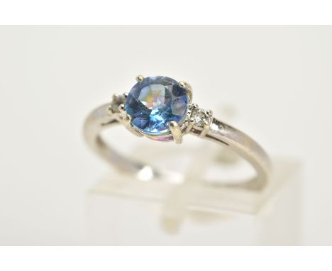 A 9CT WHITE GOLD TOPAZ RING, designed with a claw set circular cut coated topaz (mystic topaz) flanked with colourless circul