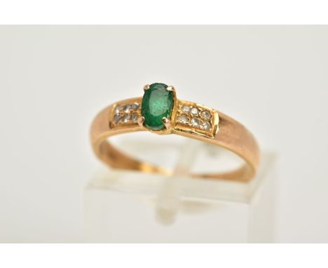 AN EMERALD AND DIAMOND RING, the yellow metal ring set with a central oval cut emerald, flanked with round brilliant cut diam