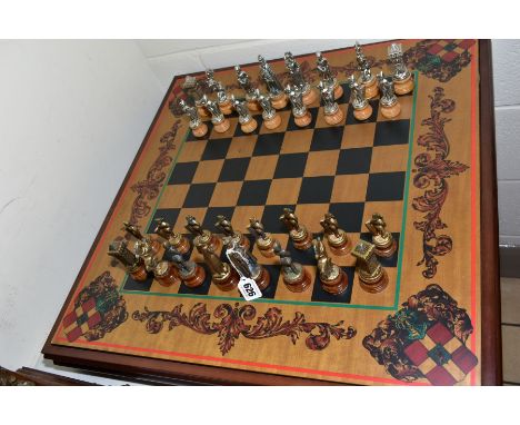 A MODERN WOODEN AND METAL CHESS SET, the board set into a storage base, height of King 10cm, heraldic designs to chess board,