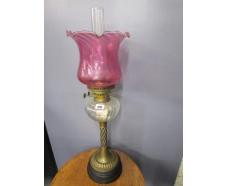 OIL LAMP, brass circular based writhen column oil lamp with cranberry glass shade in clear glass reservoir 