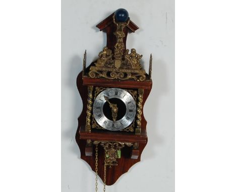 A late 20th century small Dutch frieze ''Nu Elck Syn Sin'' wall clock, the arched cornice surmounted by brass diorama finial 