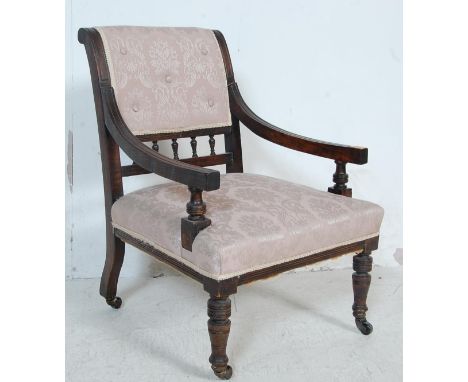 A late Victorian 19th century mahogany nursing chair having shaped arm rests with a button backrest over a turned gallery bac