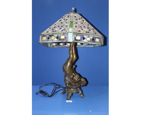 A Tiffany style lamp with ornate stained glass shade with base featuring a gymnast, 24'' tall overall, (some damage to shade)