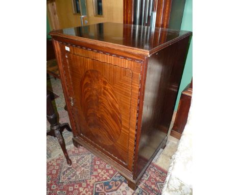 An early 20th century Mahogany Cupboard, the door having an oval flame Mahogany inset panel and having unusual edging and bea