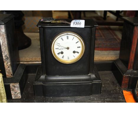 A plain slate chiming Mantle Clock having Roman numerals on a white face and a clear glass back panel, with key and pendulum,