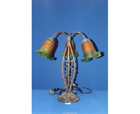 A three branch Lily table lamp having a cast metal floral base and green/orange shades, 20 1/2'' tall.