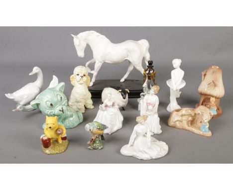 A quantity of ceramic figures. Includes Royal Doulton Winnie The Pooh, Doulton ladies, Spirit of Freedom horse, Beswick, Nao,