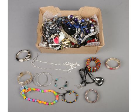 A box of assorted costume jewellery to include beaded necklaces, scrabble tile rings, bangles, etc.  