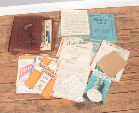 A vintage leather music bag with contents of assorted sheet and carol music scores. Examples include Annie Get Your Gun, The 