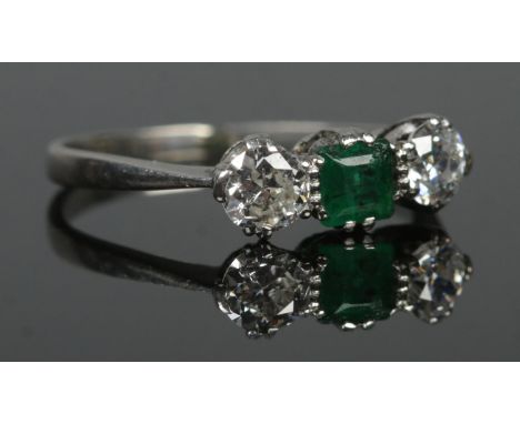 An Art Deco platinum, diamond and emerald three stone ring. Size M. 2.57g.  Slight scuff to emerald stone.