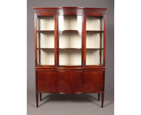 An Edwardian mahogany display cabinet raised on cupboard base and four tapering supports. Having curved central glass panel. 