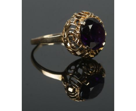 A 9ct gold ring set with a large amethyst coloured stone. Size P 1/2. 4.42g.  Band slightly misshapen.